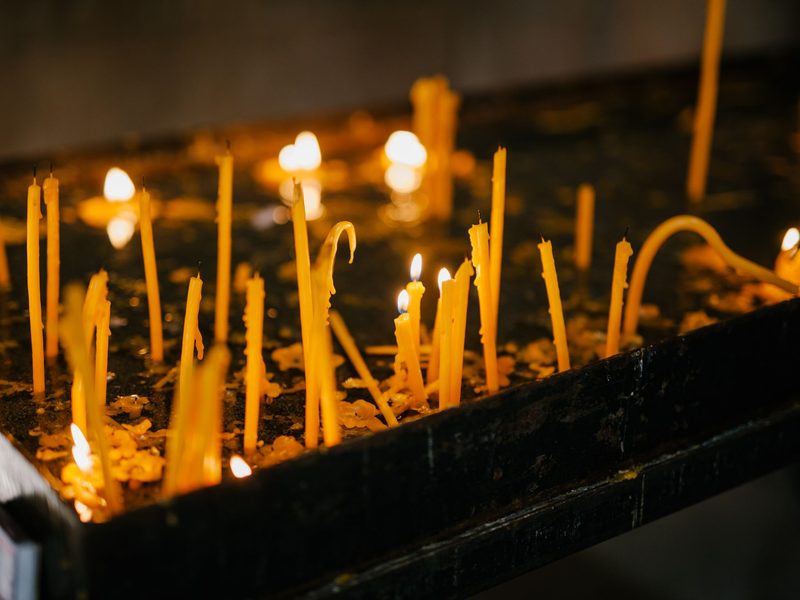 Viele brennende Gedenkkerzen auf einem Kerzenständer in einer Kapelle