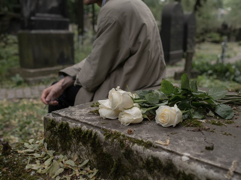 Weiße Rosen auf einem moosbewachsenen Grabstein